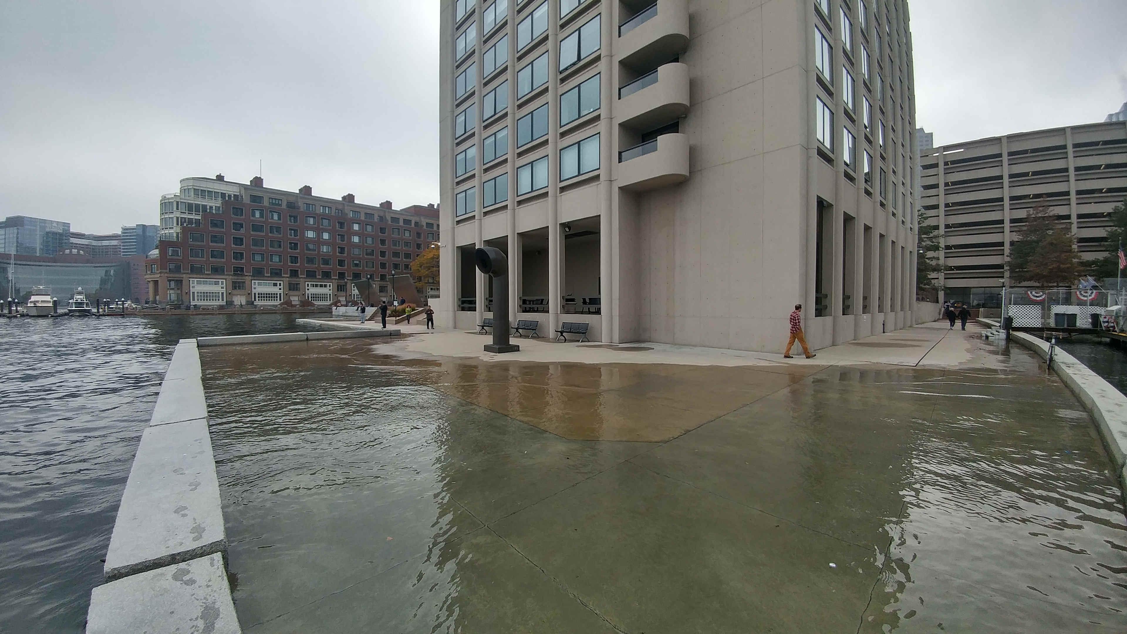 High tide flooding pushes water onto a walkway along the Boston waterfront near India Wharf, Boston, MA.