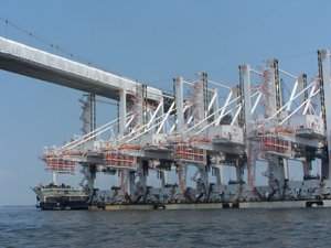 cranes being shipped under a bridge